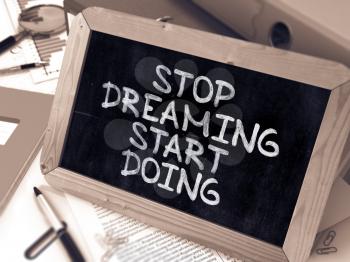 Stop Dreaming, Start Doing - Chalkboard with Hand Drawn Text, Stack of Office Folders, Stationery, Reports on Blurred Background. Toned Image. 3D Render.