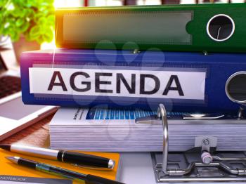 Agenda - Blue Office Folder on Background of Working Table with Stationery and Laptop. Agenda Business Concept on Blurred Background. Agenda Toned Image. 3D.