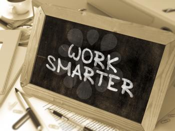 Work Smarter Handwritten by White Chalk on a Blackboard. Composition with Small Chalkboard on Background of Working Table with Office Folders, Stationery, Reports. Blurred, Toned Image. 3D Render.