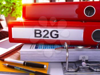 Red Office Folder with Inscription B2G on Office Desktop with Office Supplies and Modern Laptop. B2G Business Concept on Blurred Background. B2G - Toned Image. 3D Render.
