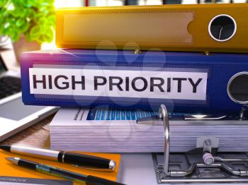 High Priority - Blue Office Folder on Background of Working Table with Stationery and Laptop. High Priority Business Concept on Blurred Background. High Priority Toned Image. 3D.