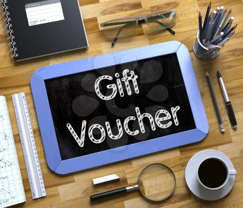Gift Voucher. Business Concept Handwritten on Blue Small Chalkboard. Top View Composition with Chalkboard and Office Supplies on Office Desk. Small Chalkboard with Gift Voucher Concept. 3d Rendering.