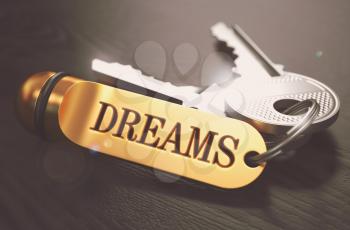Dreams - Concept on Golden Keychain over Black Wooden Background. Closeup View, Selective Focus, 3D Render. Toned Image.
