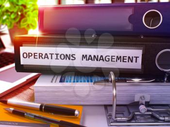 Black Ring Binder with Inscription Operations Management on Background of Working Table with Office Supplies and Laptop. Operations Management Business Concept on Blurred Background. 3D Render.