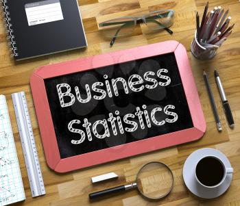 Business Statistics - Text on Small Chalkboard.Business Statistics - Red Small Chalkboard with Hand Drawn Text and Stationery on Office Desk. Top View. 3d Rendering.
