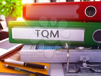 Green Office Folder with Inscription TQM - Total Quality Management - on Office Desktop with Office Supplies and Modern Laptop. TQM Business Concept on Blurred Background. TQM - Toned Image. 3D.