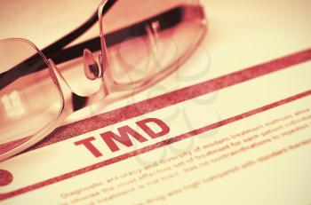 TMD - Temporomandibular Disorder - Printed Diagnosis with Blurred Text on Red Background with Pair of Spectacles. Medical Concept. 3D Rendering.