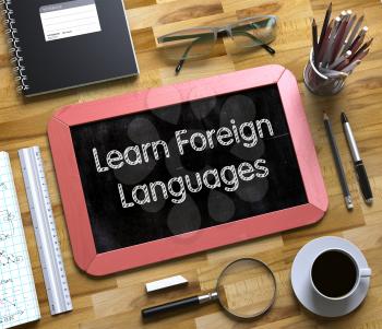 Learn Foreign Languages on Small Chalkboard. Learn Foreign Languages - Red Small Chalkboard with Hand Drawn Text and Stationery on Office Desk. Top View. 3d Rendering.