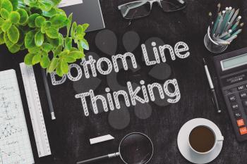 Bottom Line Thinking. Business Concept Handwritten on Black Chalkboard. Top View Composition with Chalkboard and Office Supplies. 3d Rendering. Toned Illustration.
