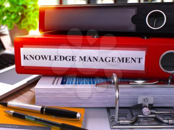 Red Ring Binder with Inscription Knowledge Management on Background of Working Table with Office Supplies and Laptop. Knowledge Management Business Concept on Blurred Background. 3D Rendering.