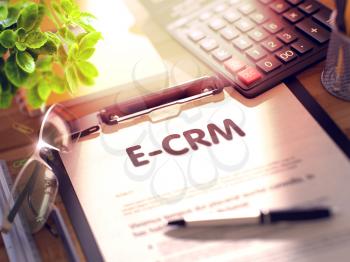 E-CRM on Clipboard. Composition with Clipboard on Working Table and Office Supplies Around. 3d Rendering. Blurred and Toned Image.
