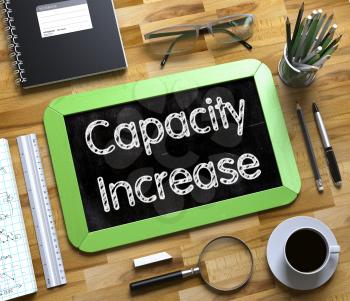 Capacity Increase - Text on Small Chalkboard.Capacity Increase - Green Small Chalkboard with Hand Drawn Text and Stationery on Office Desk. Top View. 3d Rendering.