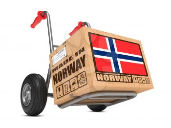 Cardboard Box with Flag of Norway and Made in Norway Slogan on Hand Truck White Background. Free Shipping Concept.