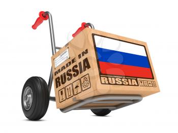 Cardboard Box with Flag of Russia and Made in Russia Slogan on Hand Truck White Background. Free Shipping Concept.
