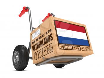 Cardboard Box with Flag of Netherlands and Made in Netherlands Slogan on Hand Truck White Background. Free Shipping Concept.