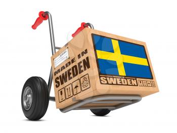 Cardboard Box with Flag of Sweden and Made in Sweden Slogan on Hand Truck White Background. Free Shipping Concept.