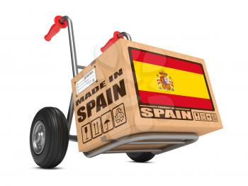 Cardboard Box with Flag of Spain and Made in Spain Slogan on Hand Truck White Background. Free Shipping Concept.