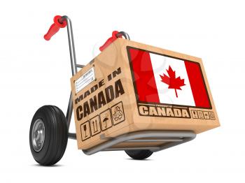 Cardboard Box with Flag of Canada and Made in Canada Slogan on Hand Truck White Background. Free Shipping Concept.