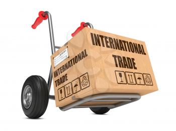 Cardboard Box with International Trade Slogan on Hand Truck White Background.