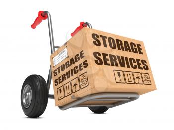 Cardboard Box with Storage Services Slogan on Hand Truck White Background.