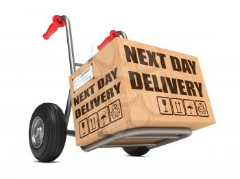 Cardboard Box with Next Day Delivery Slogan on Hand Truck White Background.
