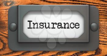 Insurance - Inscription on File Drawer Label on a Wooden Background.