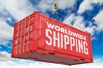 World Wide Shipping - Red Cargo Container hoisted with hook on Blue Sky Background.