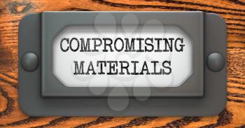 Compromising Materials - Inscription on File Drawer Label on a Wooden Background.