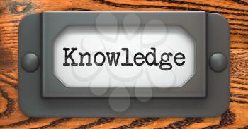 Knowledge Inscription on File Drawer Label on a Wooden Background.