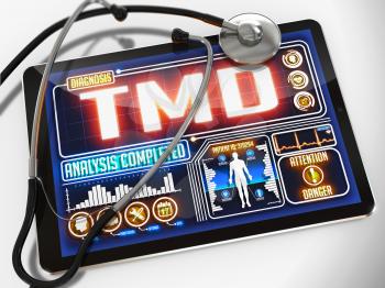 Medical Tablet with the Diagnosis of TMD on the Display and a Black Stethoscope on White Background.