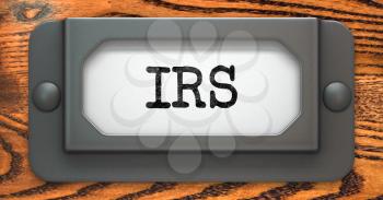 IRS Inscription on File Drawer Label on a Wooden Background.
