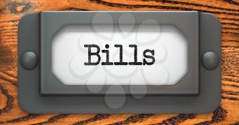 Bills Inscription on File Drawer Label on a Wooden Background.