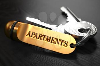 Keys with Word Apartaments on Golden Label over Black Wooden Background. Closeup View, Selective Focus, 3D Render.