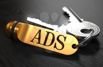 Keys and Golden Keyring with the Word Ads over Black Wooden Table with Blur Effect.