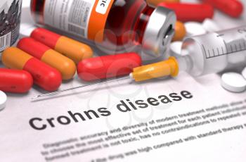 Crohns Disease - Printed Diagnosis with Blurred Text. On Background of Medicaments Composition - Red Pills, Injections and Syringe.