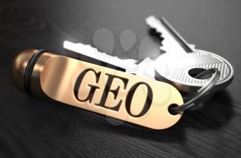 Keys and Golden Keyring with the Word GEO over Black Wooden Table with Blur Effect.