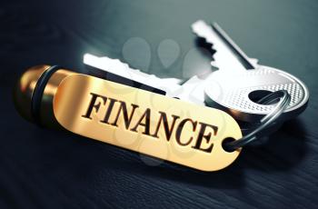Keys and Golden Keyring with the Word Finance over Black Wooden Table with Blur Effect. Toned Image.
