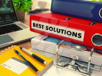 Red Office Folder with Inscription Best Solutions on Office Desktop with Office Supplies and Modern Laptop. Business Concept on Blurred Background. Toned Image.