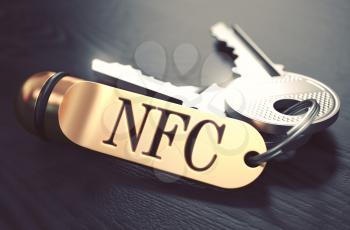Keys and Golden Keyring with the Word NFC - Near Field Communication - over Black Wooden Table with Blur Effect. Toned Image.