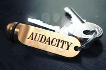 Keys with Word Audacity on Golden Label over Black Wooden Background. Closeup View, Selective Focus, 3D Render. Toned Image.
