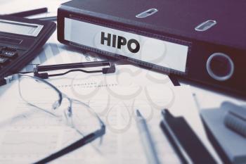 Ring Binder with inscription HiPo - High Potential - on Background of Working Table with Office Supplies, Glasses, Reports. Toned Illustration. Business Concept on Blurred Background.
