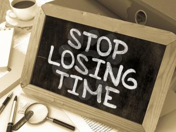 Stop Losing Time. Motivational Quote Handwritten on Chalkboard. Composition with Small Chalkboard on Background of Working Table with Ring Binders, Office Supplies, Reports. Blurred Background. Toned 