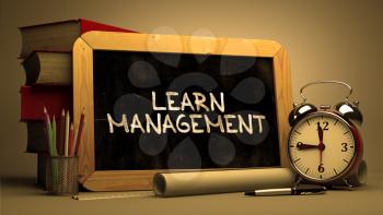 Learn Management - Chalkboard with Hand Drawn Text, Stack of Books, Alarm Clock and Rolls of Paper on Blurred Background. Toned Image. Motivational Quote.