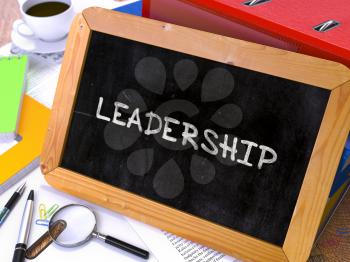 Handwritten Leadership on a Chalkboard. Composition with Chalkboard and Ring Binders, Office Supplies, Reports on Blurred Background. Toned Image.