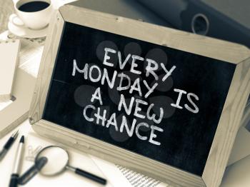 Every Monday is a New Chance. Inspirational Quote Handwritten on Chalkboard. Composition with Small Chalkboard on Working Table with Ring Binders, Office Supplies, Reports. Blurred, Toned Image.