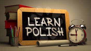 Learn Polish - Chalkboard with Hand Drawn Text, Stack of Books, Alarm Clock and Rolls of Paper on Blurred Background. Toned Image.