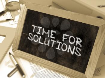 Time for Solutions Handwritten on Chalkboard. Composition with Small Chalkboard on Background of Working Table with Ring Binders, Office Supplies, Reports. Blurred Background. Toned Image.