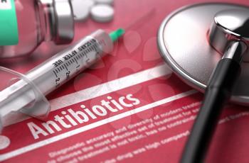 Antibiotics - Medical Concept on Red Background with Blurred Text and Composition of Pills, Syringe and Stethoscope.