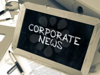 Corporate News Handwritten by White Chalk on a Blackboard. Composition with Small Chalkboard on Background of Working Table with Office Folders, Stationery, Reports. Blurred, Toned Image.