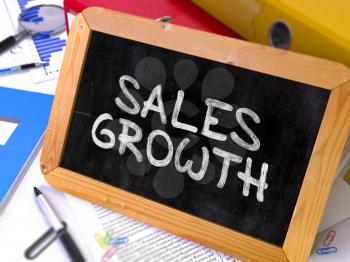 Handwritten Sales Growth on a Chalkboard. Composition with Chalkboard and Ring Binders, Office Supplies, Reports on Blurred Background. Toned Image.